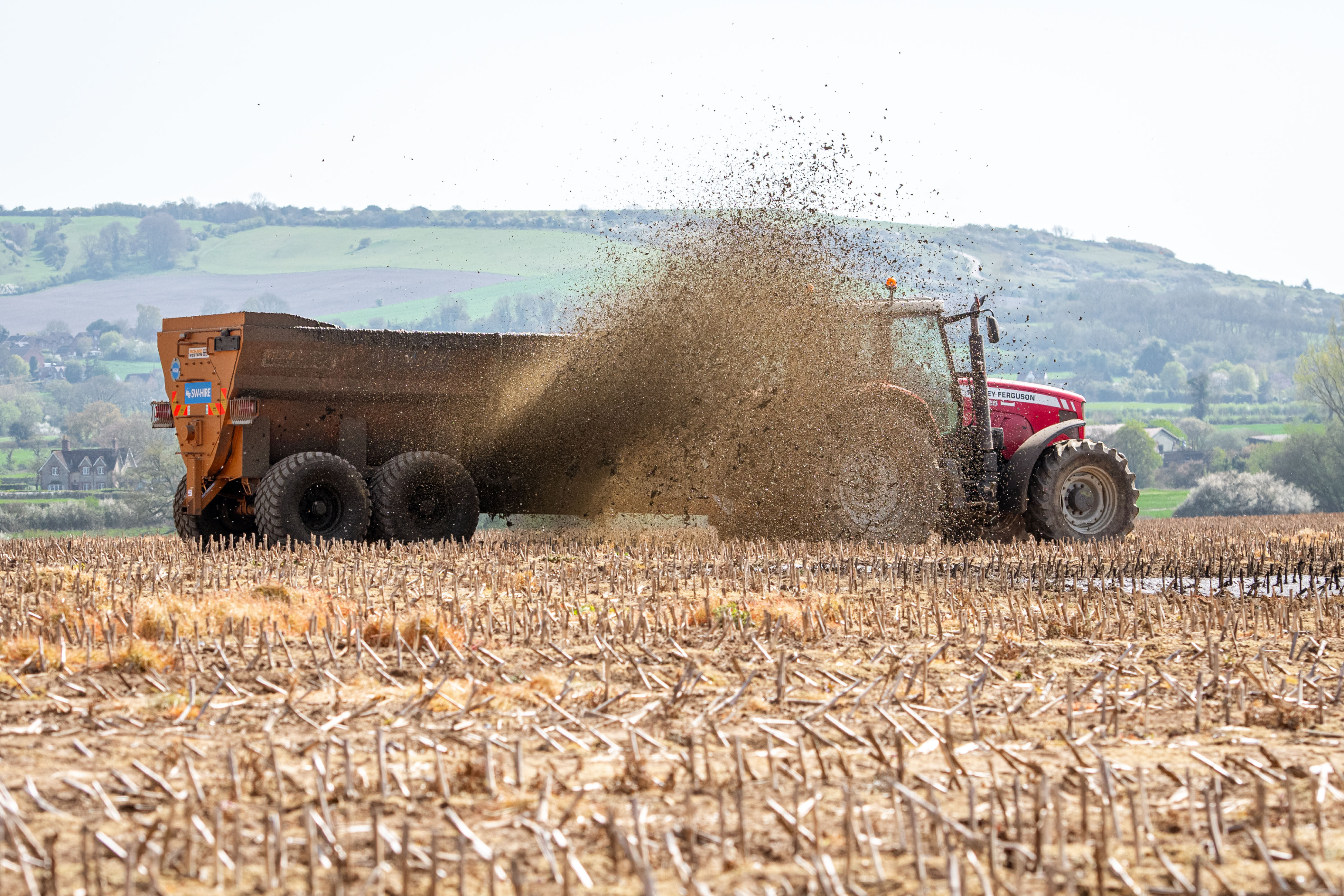 Richard Western side discharge spreader throwing out slurry from the side door on to a maize stubble field